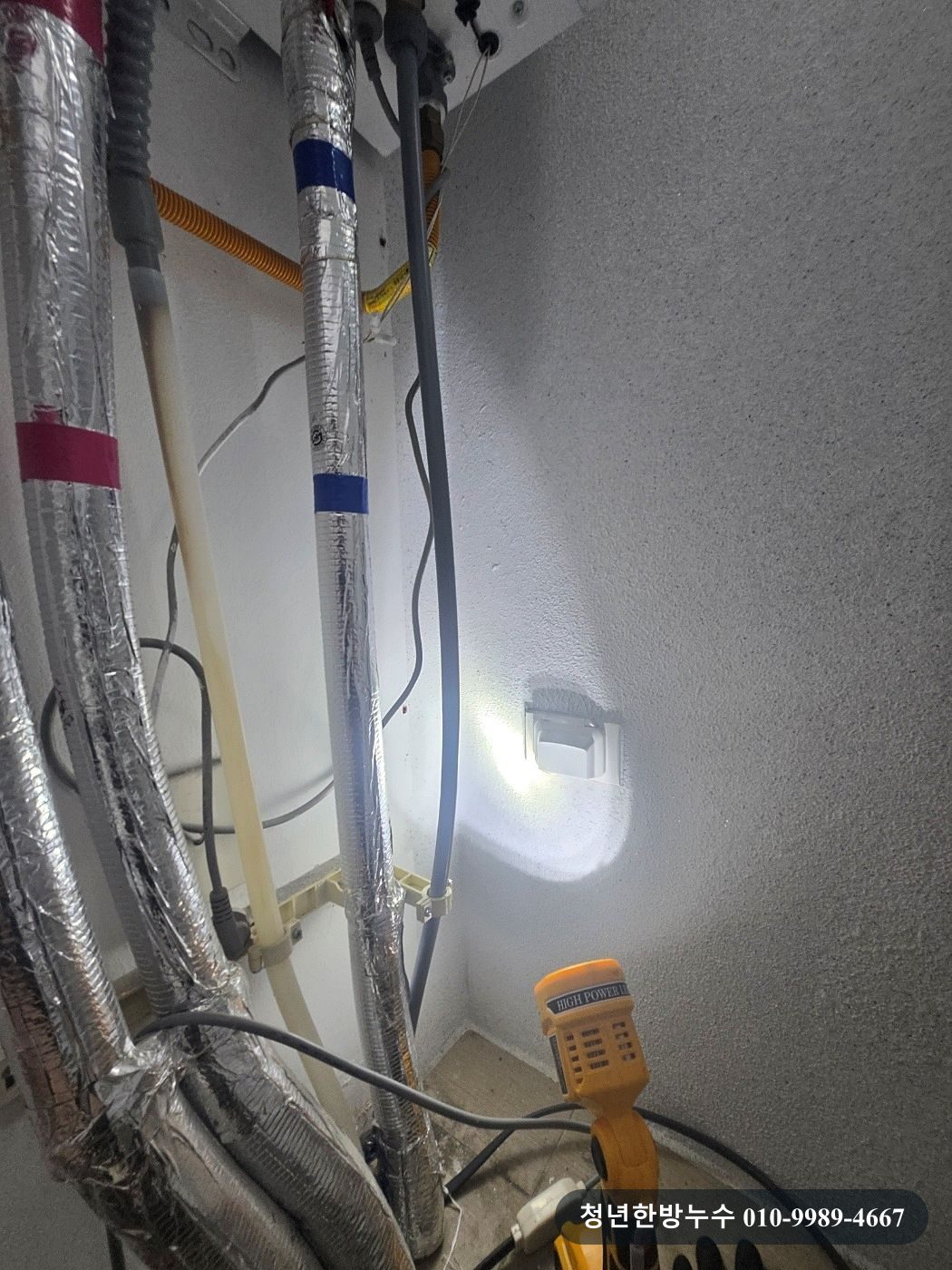 보일러 아래로 연결된 배관과 점검 호스입니다.
